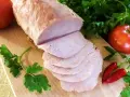 Pokrojony schab gotowany 2 razy po 10 minut, podany z pomidorami, papryczkami chili i natką pietruszki na desce.