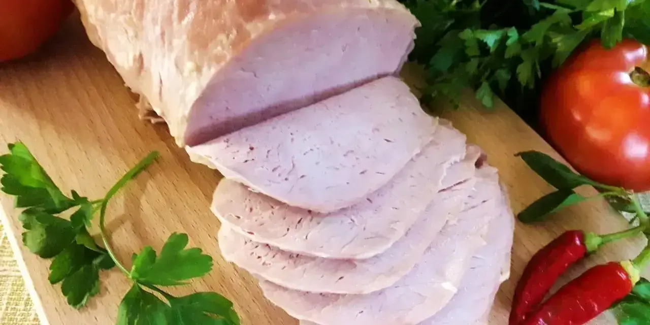 Pokrojony schab gotowany 2 razy po 10 minut, podany z pomidorami, papryczkami chili i natką pietruszki na desce.