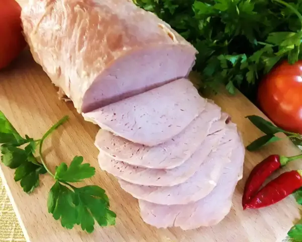 Pokrojony schab gotowany 2 razy po 10 minut, podany z pomidorami, papryczkami chili i natką pietruszki na desce.