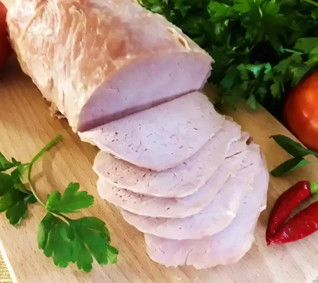 Pokrojony schab gotowany 2 razy po 10 minut, podany z pomidorami, papryczkami chili i natką pietruszki na desce.