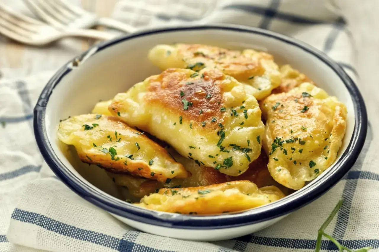 Złociste pierogi ruskie, pachnące jak u babci, posypane natką pietruszki. Przepis babci na te pyszności to skarb!